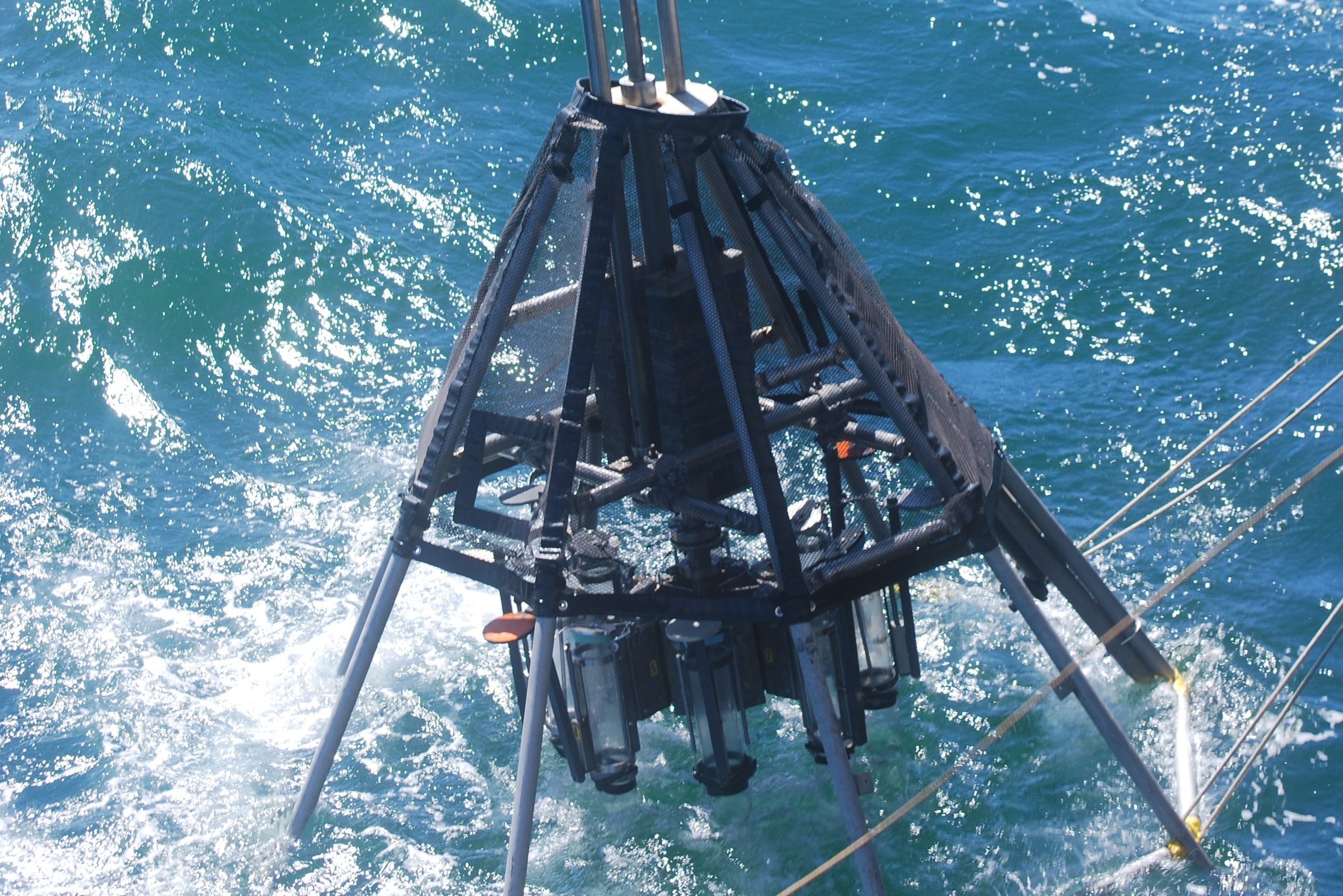 The multicore is a teepee like structure with a strong frame surrounding 8 to 12 individual cores. In this image the multicore is just touching the water as it is deployed.